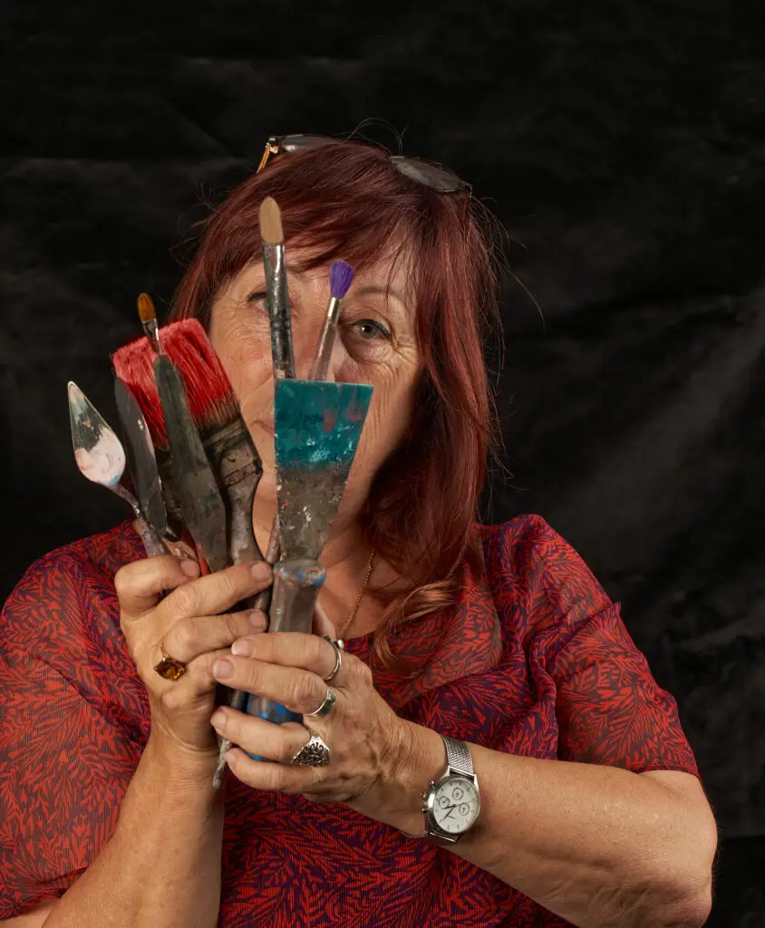 Photo de Patricia Perrier tenant des pinceaux et couteaux